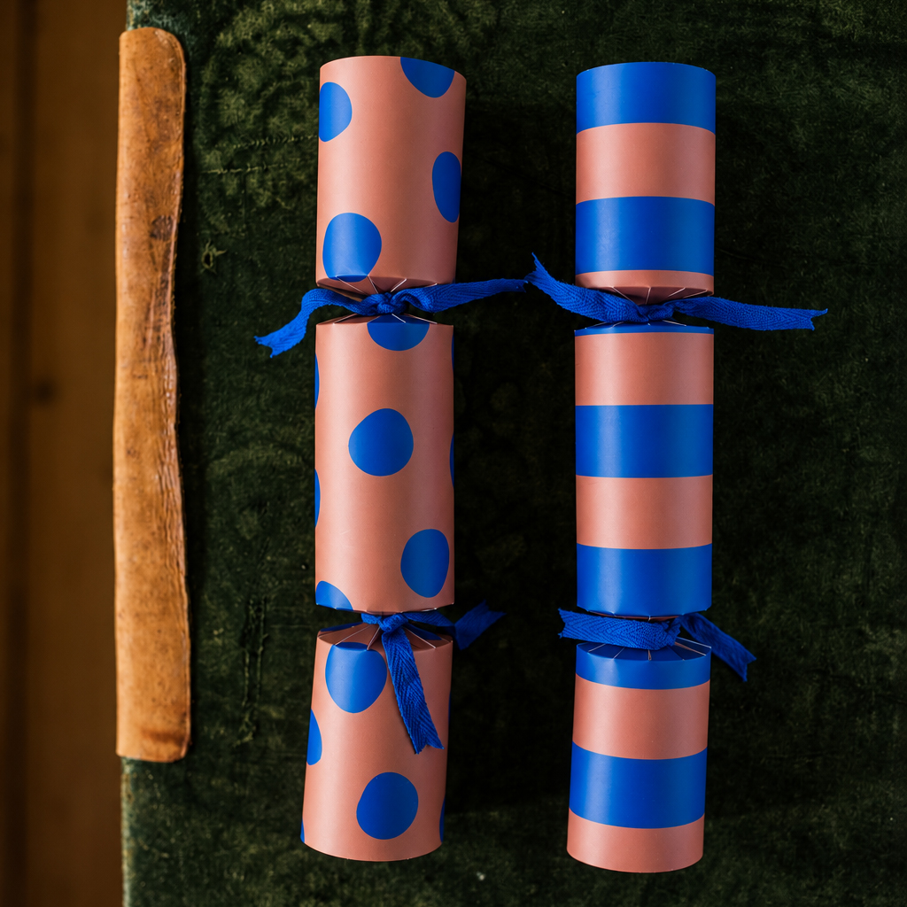 4143knallbonbonsblauepunkte Avayves Feine Papeterie Und Geschenke Für Babys Und Kids Eight peach and blue patterned party crackers tied with blue ribbons, arranged in two columns.