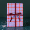 Purple gift box with orange grid pattern tied with a red ribbon on a dark green background.