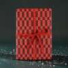 Gift box wrapped in red and burgundy checker paper with a red ribbon bow, on a dark green backdrop.