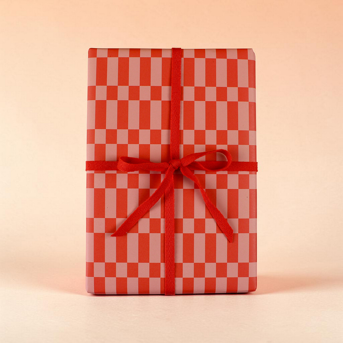 Gift box wrapped in red-and-pink checker paper tied with a red ribbon bow.