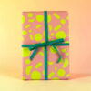 Pink gift box with neon yellow geometric patterns and a teal ribbon bow