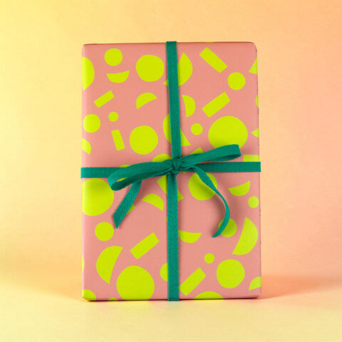 Pink gift box with neon yellow geometric patterns and a teal ribbon bow