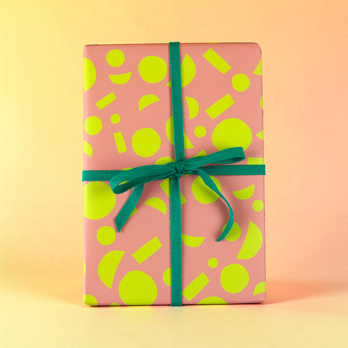 Pink gift box with neon yellow geometric patterns and a teal ribbon bow