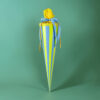 Tall gift box wrapped in blue and yellow striped paper with blue ribbon and yellow tissue on top against a green background.