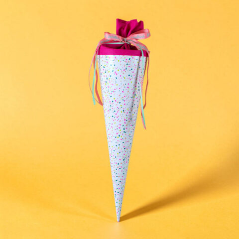 Decorated gift cone with confetti pattern and ribbons against a yellow background.
