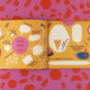 Open children’s book spread with orange pages and German phrases like 'DAS BIN ICH' surrounded by shapes.