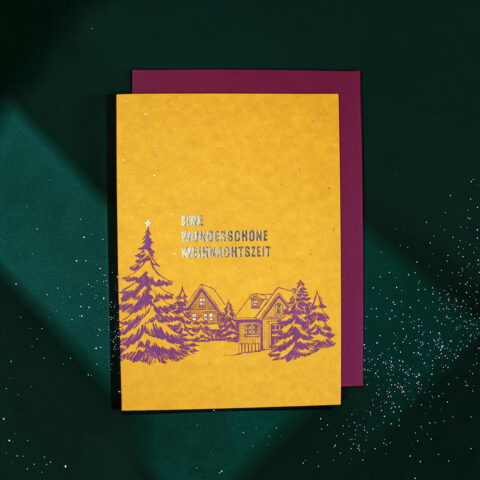 Yellow holiday card with purple winter village illustration on a green background; German text reads 'Eine wunder schöne Weihnachtszeit' and a purple backing shows behind.
