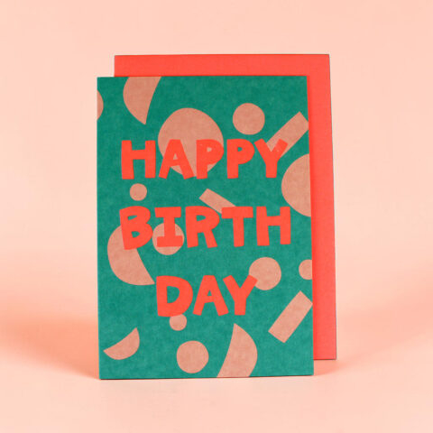 Bright teal birthday card with bold red 'HAPPY BIRTHDAY' text and abstract shapes, set against a pink background.