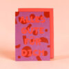 Front of a purple greeting card with red decorative shapes and the German message 'ALLES GUTE FÜR DICH'.