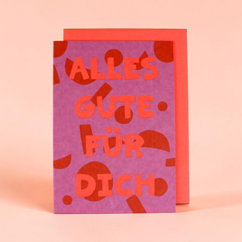 Front of a purple greeting card with red decorative shapes and the German message 'ALLES GUTE FÜR DICH'.