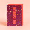 2387gkgutscheinterrazzonronorange Avayves Feine Papeterie Und Geschenke Für Babys Und Kids Purple gift box with multicolored confetti pattern and large vertical orange text, set against a peach background.