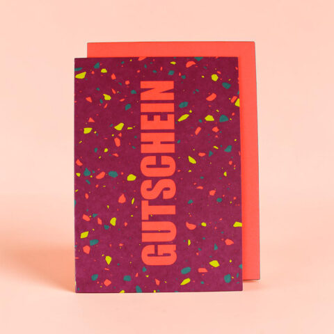 Purple gift box with multicolored confetti pattern and large vertical orange text, set against a peach background.