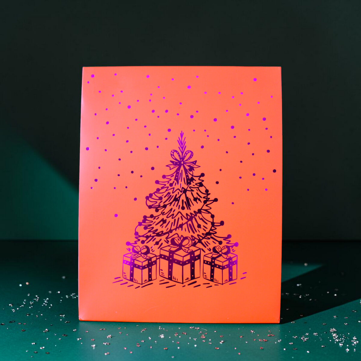 4185geschenktaschelweihnachtsbaum02 Avayves Feine Papeterie Und Geschenke Für Babys Und Kids Decorative orange panel with purple polka dots and a purple Christmas tree and gifts illustration on a dark background