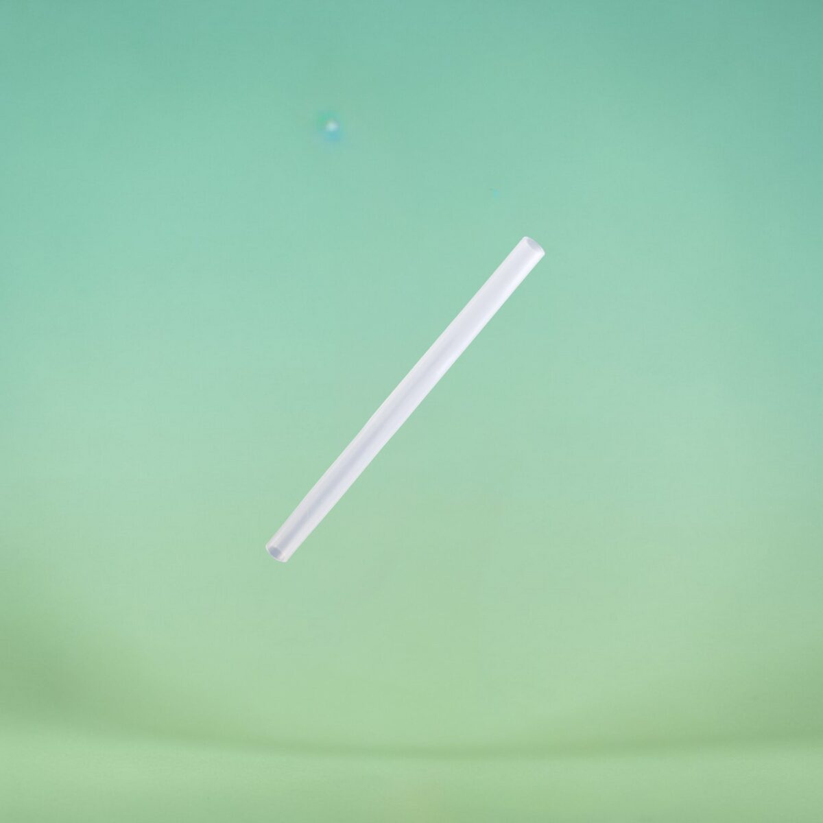 White plastic straw angled diagonally across a mint-green background.