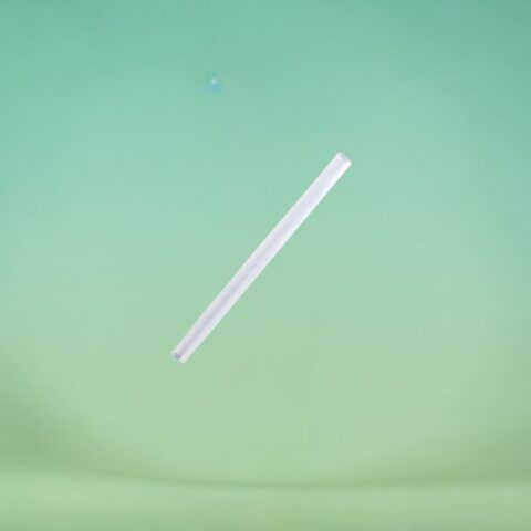 White plastic straw angled diagonally across a mint-green background.