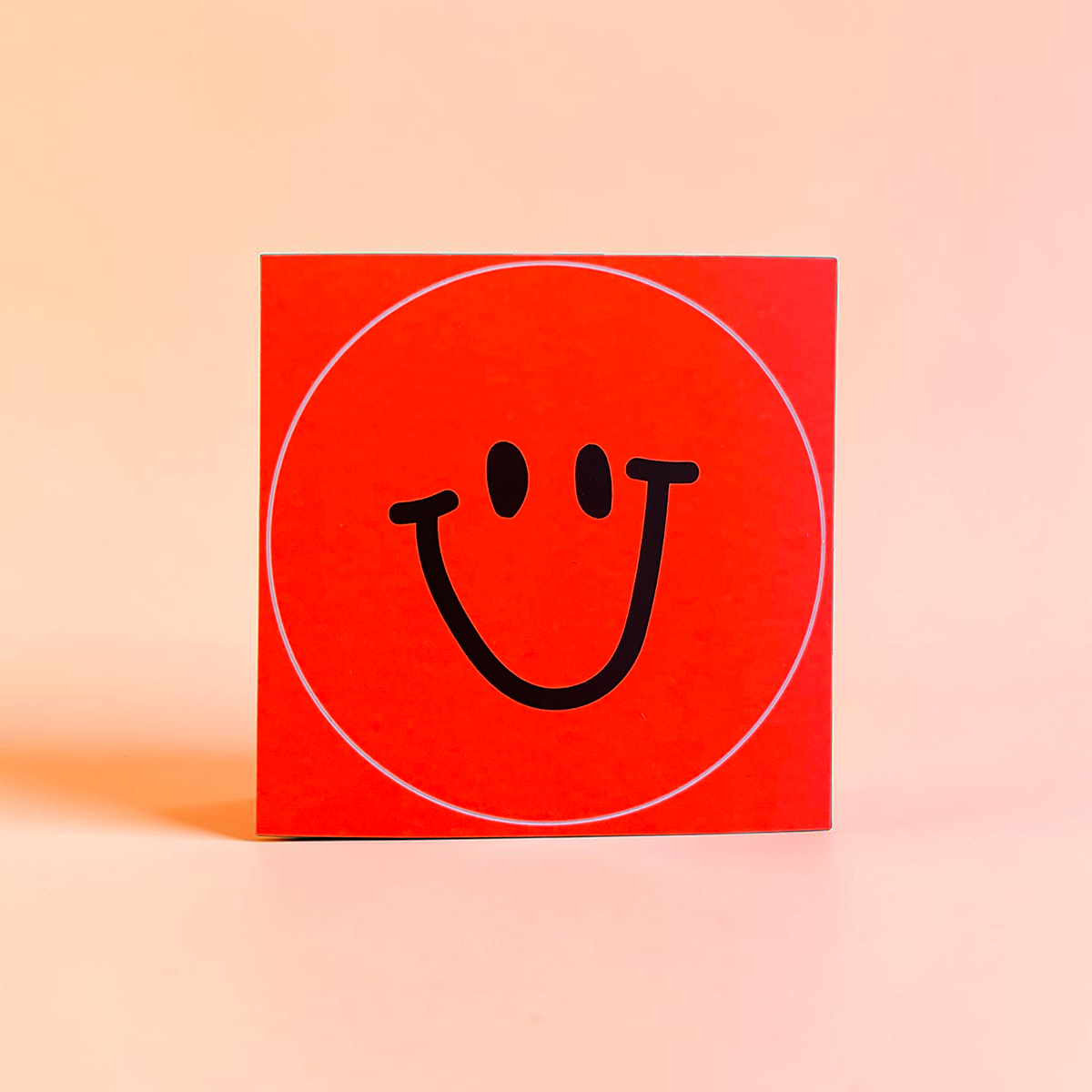 5899aufklebersmileneonrot Avayves Feine Papeterie Und Geschenke Für Babys Und Kids Red square box featuring a bold black smiley face inside a white circular outline on a bright red background.