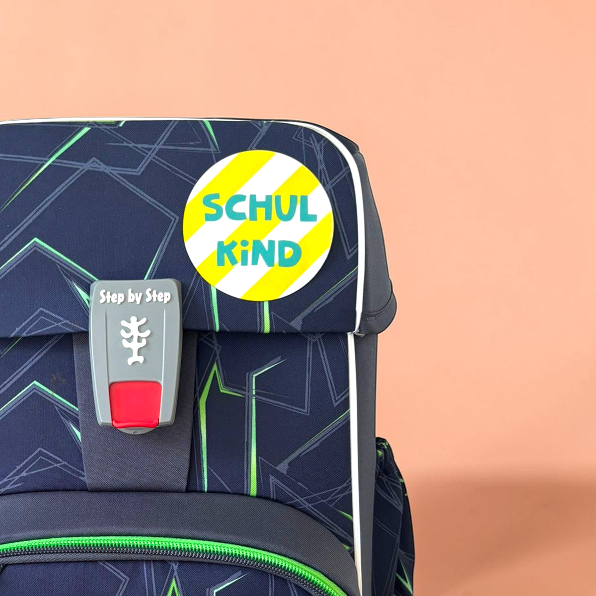 Backpack front with a bright yellow diagonal 'SCHUL KIND' sticker and a gray latch lock.