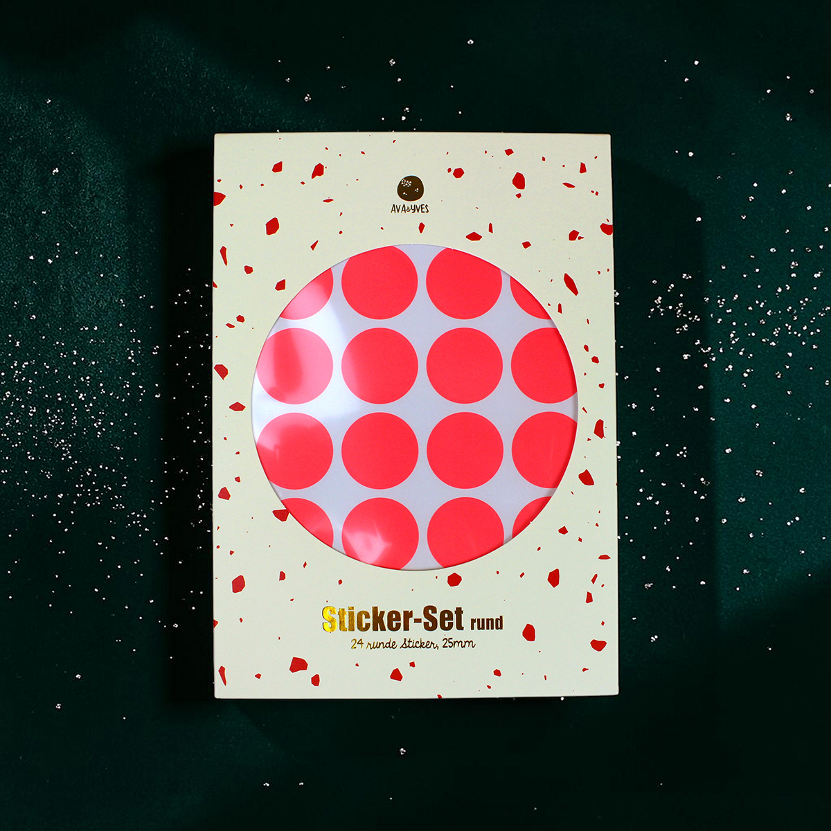 4188enveloperoundstickerneonrot Avayves Feine Papeterie Und Geschenke Für Babys Und Kids Packaging for Sticker-Set rund with a circular window showing bright pink polka-dotted stickers on white backing, scattered confetti on a green background.