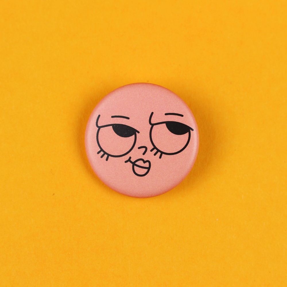 Pink round button with a sleepy, kissy-face emoji on a bright yellow background, centered in the image