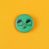 Green circular button with a cartoon face sticking out its tongue on a bright yellow background