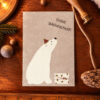 German Christmas card with a white polar bear looking up, wearing a small red hat; caption Frohe Weihnachten on beige background.