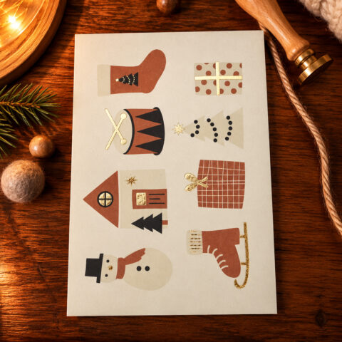Seasonal card on a wooden table featuring stylized icons: stocking, gifts, drum, tree, house, snowman, and ice skate.