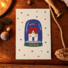 Seasonal card featuring a snow globe with a cozy house inside and 'HOHOHO' on the base, surrounded by colorful dots and a wooden background.