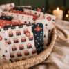 4138adventcalendarhaeuser03 Avayves Feine Papeterie Und Geschenke Für Babys Und Kids Decorative Advent calendar bags arranged in a woven basket with festive patterns and red numbers.