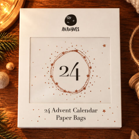 White Advent calendar packaging with a circular star design and the text '24 Advent Calendar Paper Bags' (brand Ava&Yes) on a wooden surface.