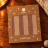 Brown starry packaging for Ava & Yves 24 paper bags on a wooden table, warm lighting.