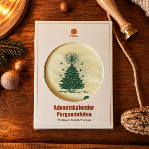 Boxed Advent calendar with a circular window showing a green Christmas tree design on white parchment, on a wooden table.