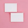 Two white envelopes on a pink background, one above the other.