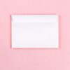White envelope lying flat on a pastel pink background, closed and sealed.