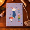 Purple lavender Christmas card featuring a cartoon dachshund in a blue starry coat and red hat, with the vertical text 'FROHES FEST' and colorful confetti dots.